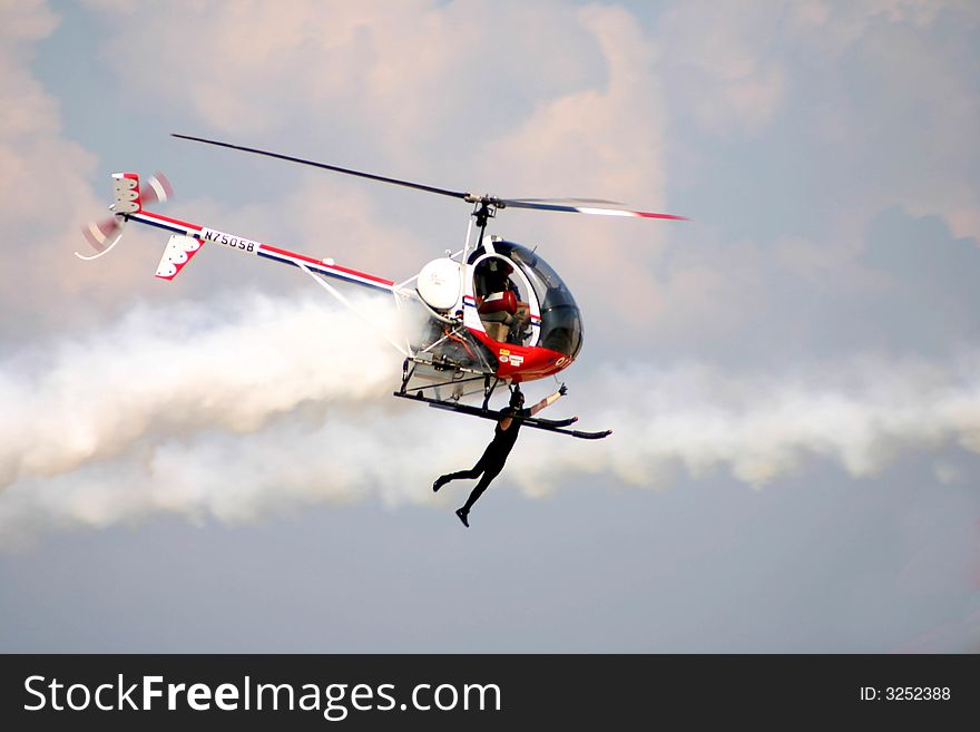 This photo was taken at the St. Pete. Air Fest. The man flying from the helicopter was on a biplane and transferred himself from the biplane to the helicopter in mid air. This photo was taken at the St. Pete. Air Fest. The man flying from the helicopter was on a biplane and transferred himself from the biplane to the helicopter in mid air.