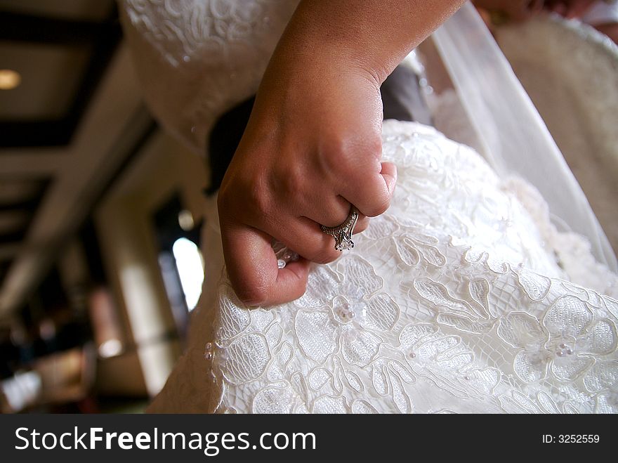 A close shot of a bride's hand as she lifts her dress slightly. A close shot of a bride's hand as she lifts her dress slightly.