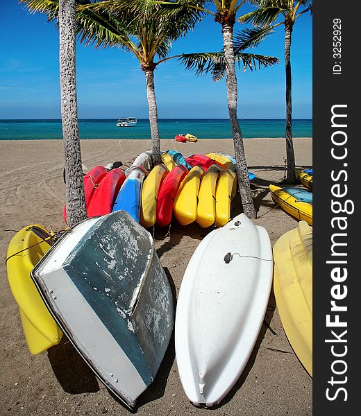 Morning shot of rental kayaks stowed on beach beside tropical bay