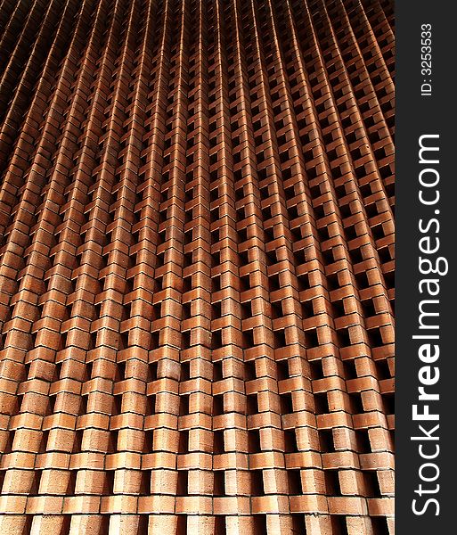 A upward converging perspective of an up-lighted brick wall created by stacking bricks in an alternating angular arrangement.