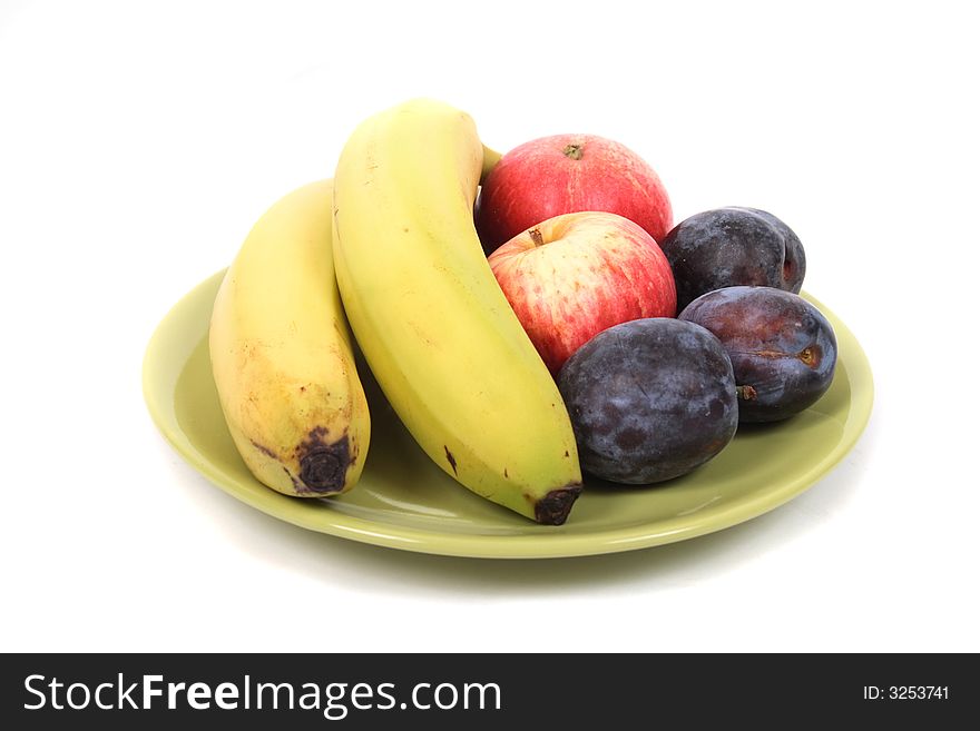 Fruits (banana, plums, apple) on the green plate