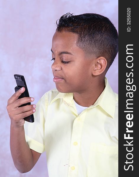 A young boy holding a cell phone looking at it in discust. A young boy holding a cell phone looking at it in discust