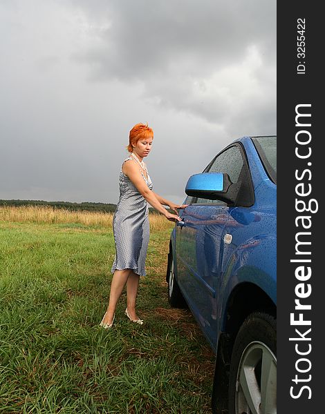 Red-haired woman in dress with blue car