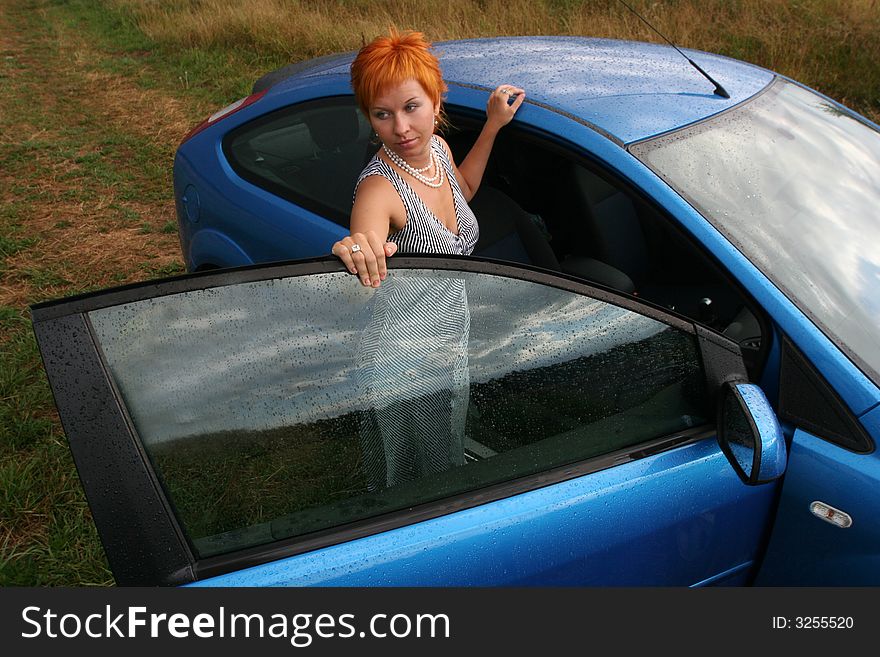 Red-haired woman in dress with blue car