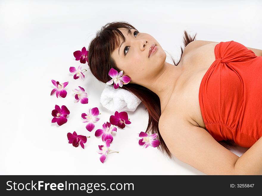 An asian women lying amongst flowers in a studio. An asian women lying amongst flowers in a studio