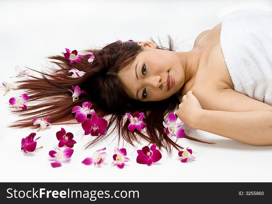 An asian women lying amongst flowers in a studio. An asian women lying amongst flowers in a studio