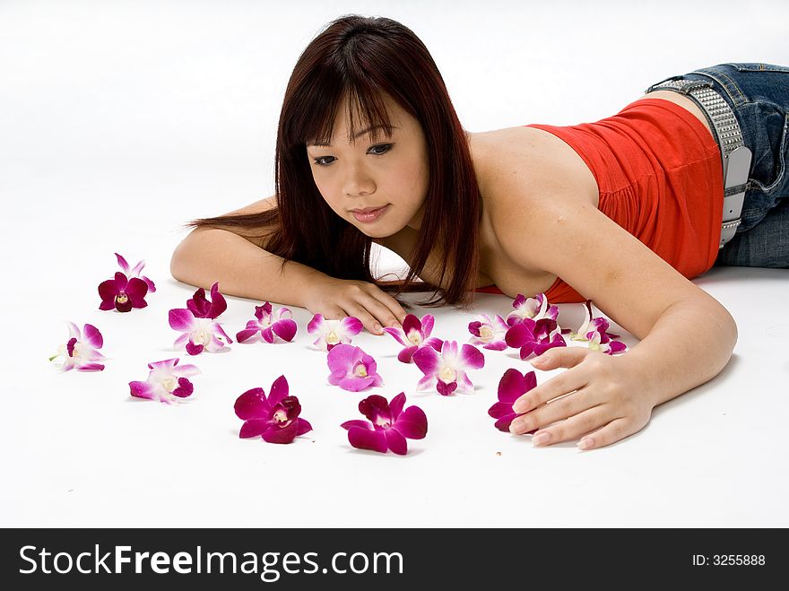 An asian women lying amongst flowers in a studio. An asian women lying amongst flowers in a studio