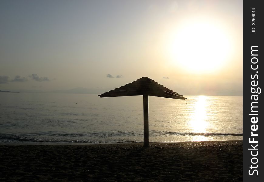 Sunrise on the beach with a lonely umbrella