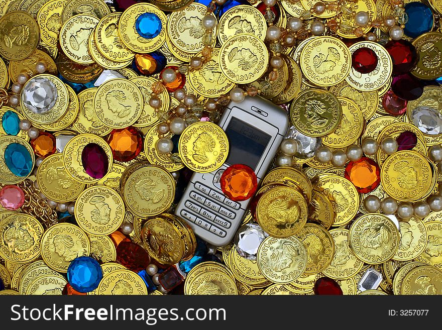 Vivid picture of a cell phone in a pile of jewels - ideal for illustrating the essential role of communication in financial prosperity. Vivid picture of a cell phone in a pile of jewels - ideal for illustrating the essential role of communication in financial prosperity.