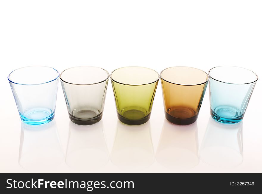 Colorful water glasses over a white reflective background