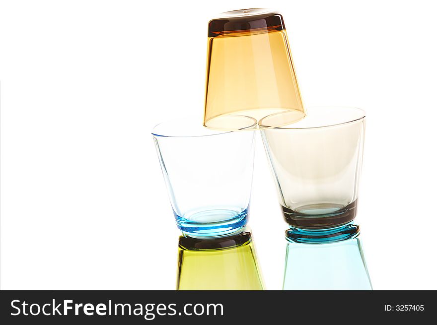 Colorful empty water glasses stacked over a white background