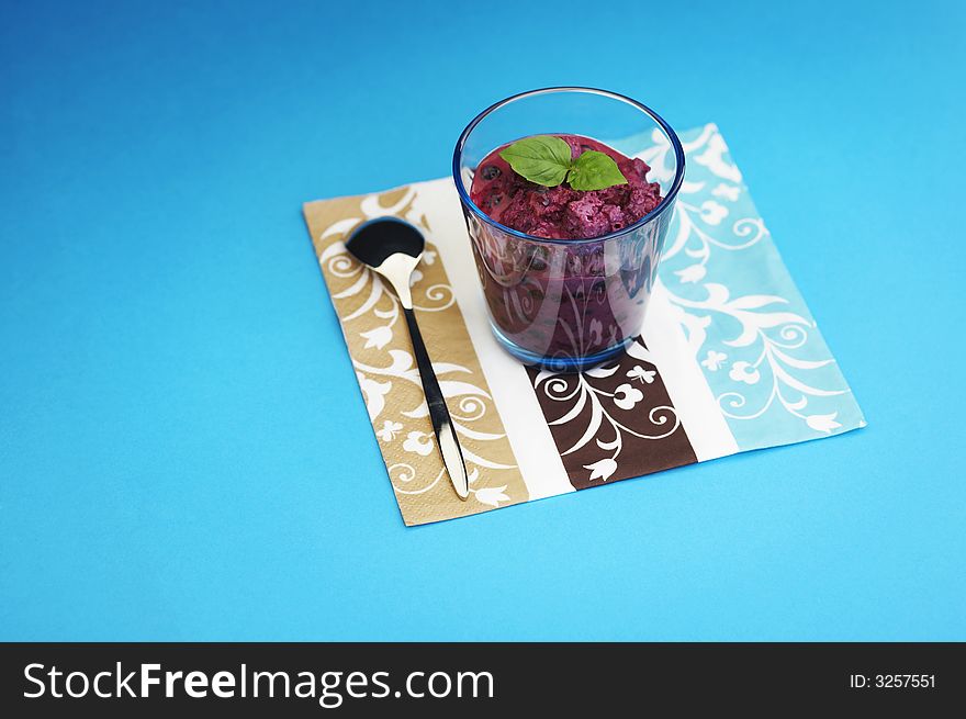 Glass of home made bilberry yogurt with bread crumbs over a blue background