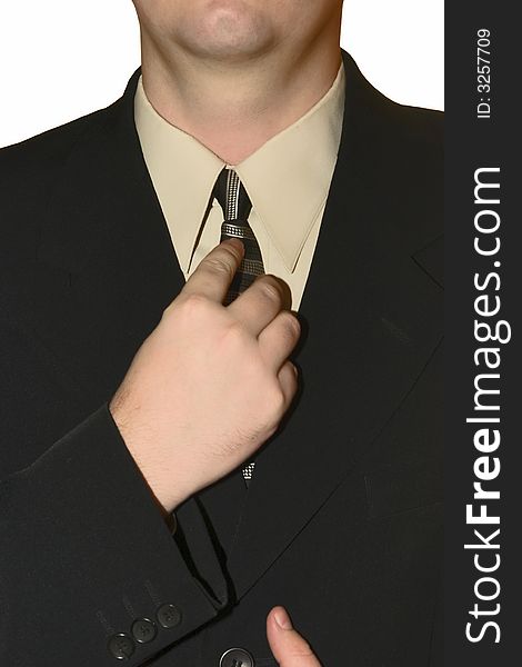 Young man in a black strict suit corrects for a tie on a white background. Young man in a black strict suit corrects for a tie on a white background