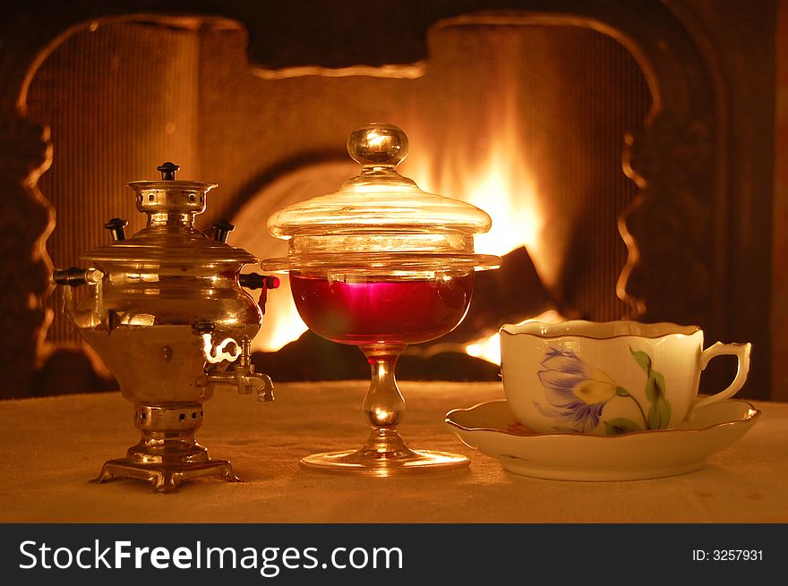 Russian style composition with a samovar, jam, and a cup if tea against the fire.