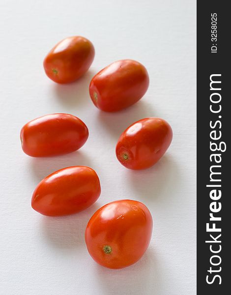 Roma tomatoes on a white ready for roasting