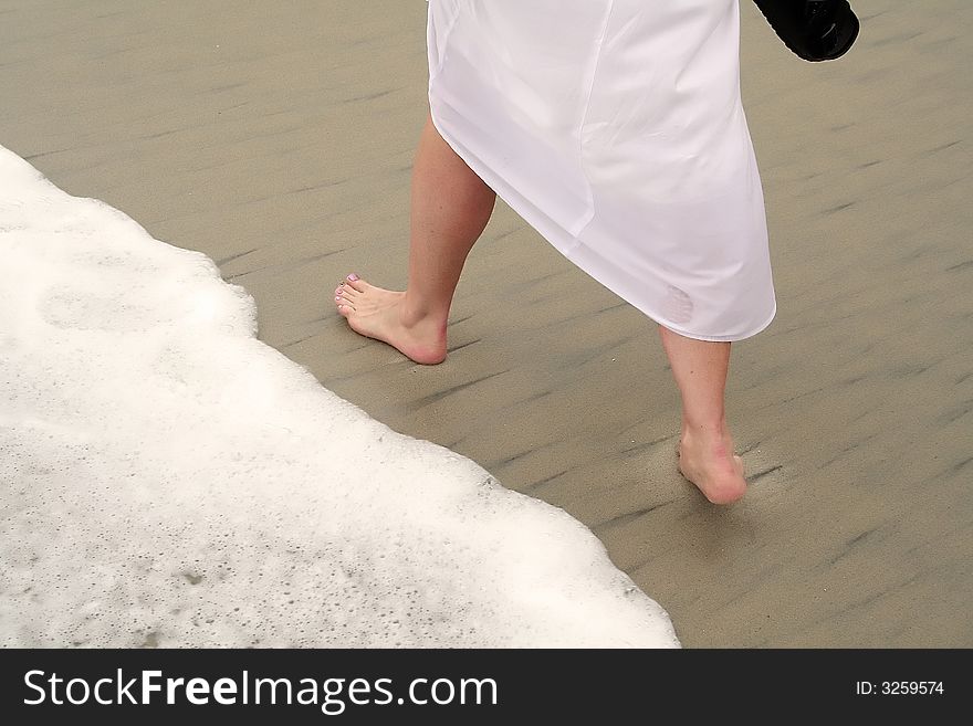 A lady on the beach walking by a wave. A lady on the beach walking by a wave