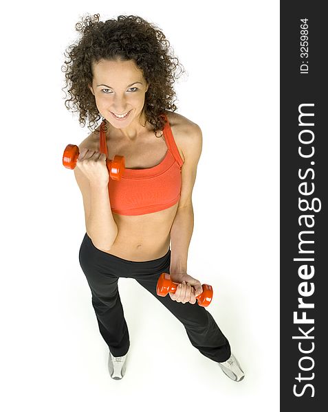 Young, beautiful woman working out with dumbbells. Smiling and looking at camera. Isolated od white in studio, high angle view. Whole body. Young, beautiful woman working out with dumbbells. Smiling and looking at camera. Isolated od white in studio, high angle view. Whole body