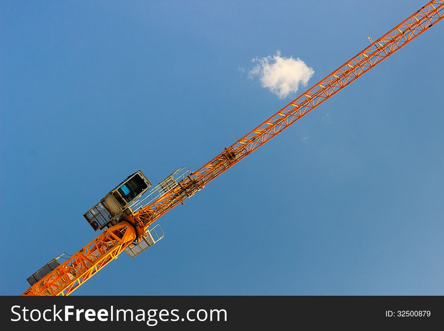 Low angle view of tall crane on modern construction site, blue sky and cloudscape background. Low angle view of tall crane on modern construction site, blue sky and cloudscape background