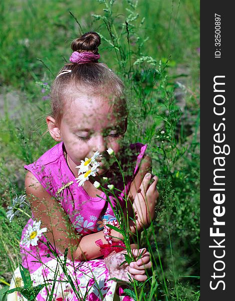 A child smelling wild flowers with closed eyes. A child smelling wild flowers with closed eyes