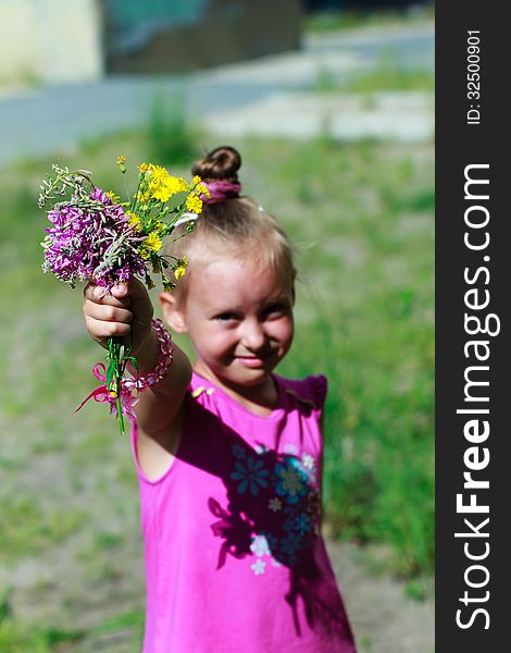 A child stretched out his hand with a bouquet, blurred background. A child stretched out his hand with a bouquet, blurred background