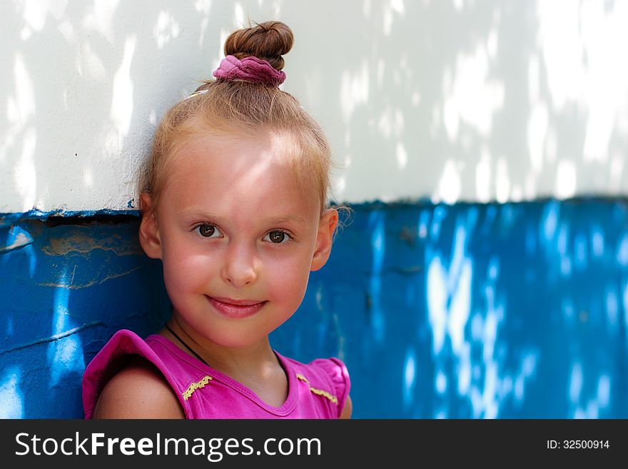 A portrait of a cute little girl near the wall in a shade. A portrait of a cute little girl near the wall in a shade