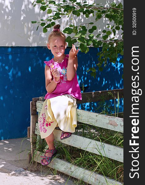 A portrait of a cute little girl holding candy in a tree shade. A portrait of a cute little girl holding candy in a tree shade