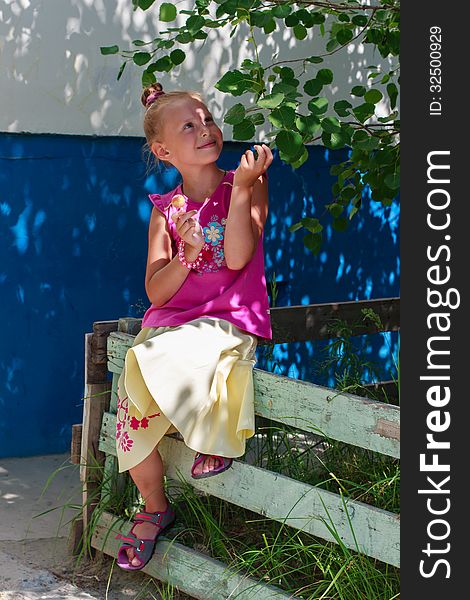 A portrait of a cute little girl holding candy in a tree shade. A portrait of a cute little girl holding candy in a tree shade