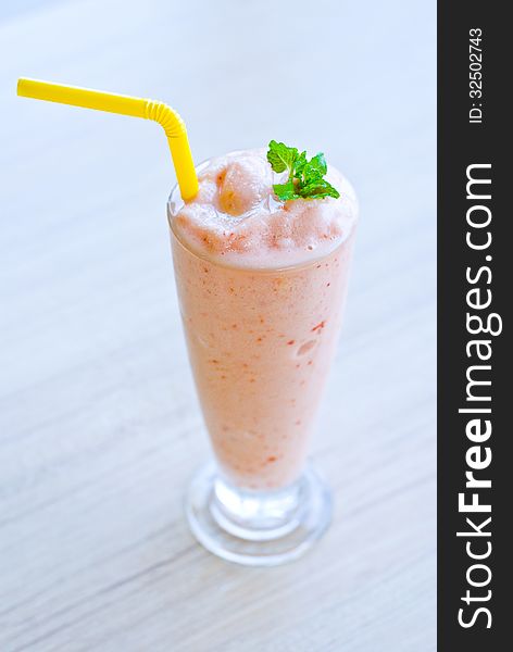 Glass of strawberry smoothie top with pepper mint on table