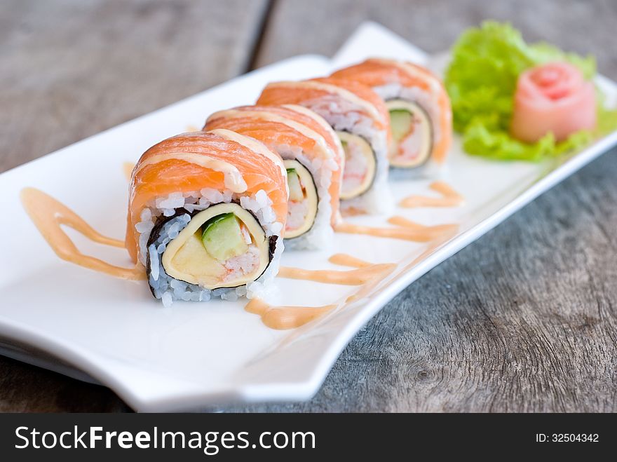 Salmon sashimi roll on white plate topping with cream sauce