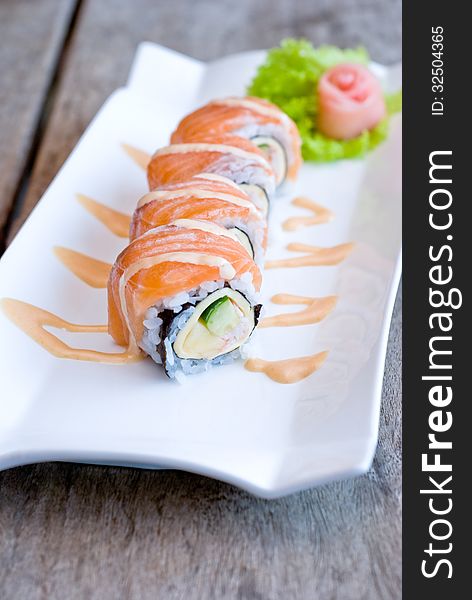 Salmon sashimi roll on white plate topping with cream sauce. Salmon sashimi roll on white plate topping with cream sauce