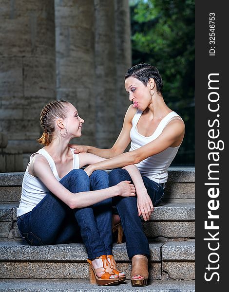 Family, mother and daughter sit and chat on the steps of the library