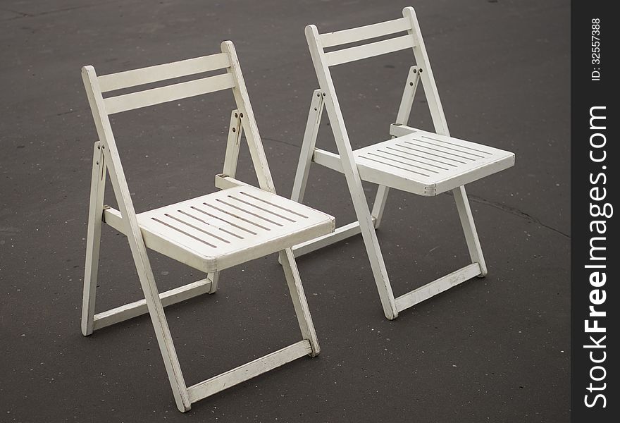 Two white folding chairs together