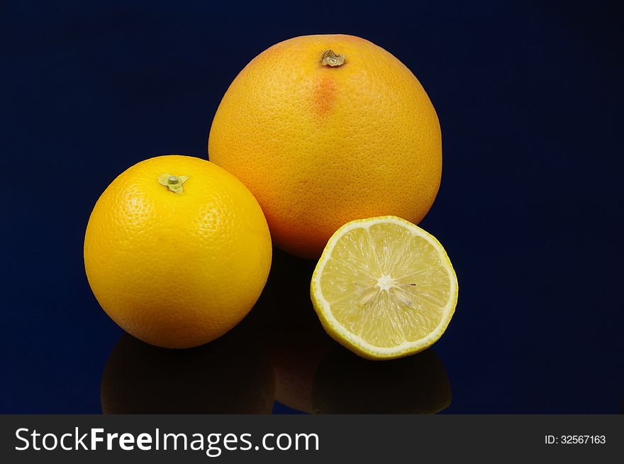 The photograph shows citrus fruits: grapefruit, orange and lemon placed on a blue background. The photograph shows citrus fruits: grapefruit, orange and lemon placed on a blue background.