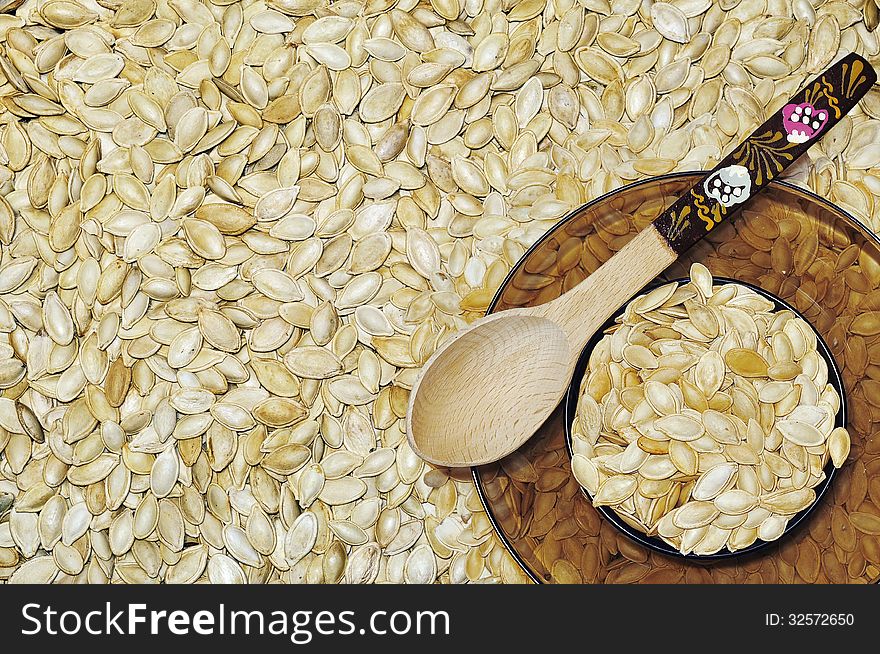 Plate of filled with pumpkin seeds stands on pumpkin seeds