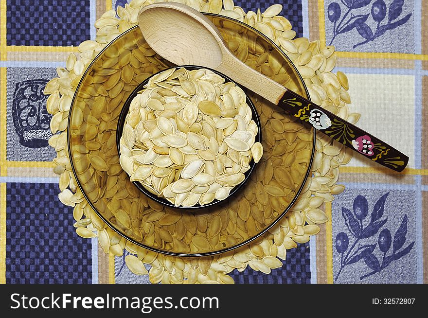 Plate of filled with pumpkin seeds stands on pumpkin seeds