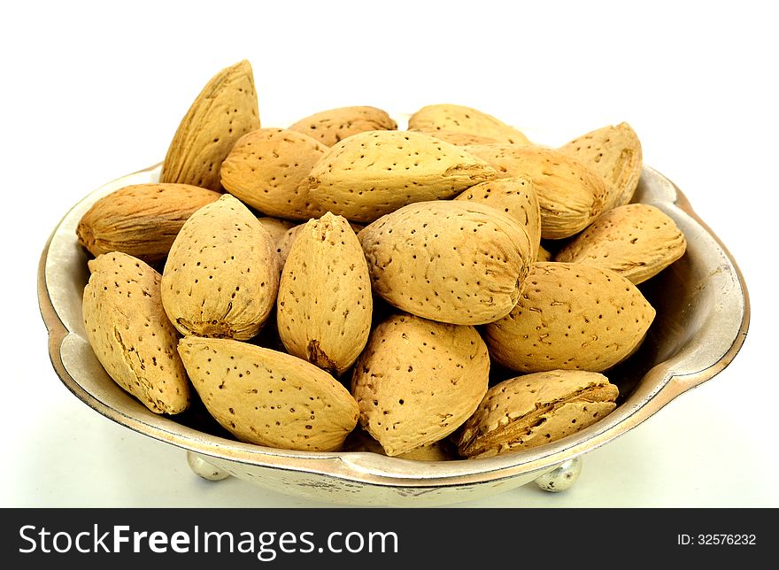 A small metal dish of almonds in the shell.