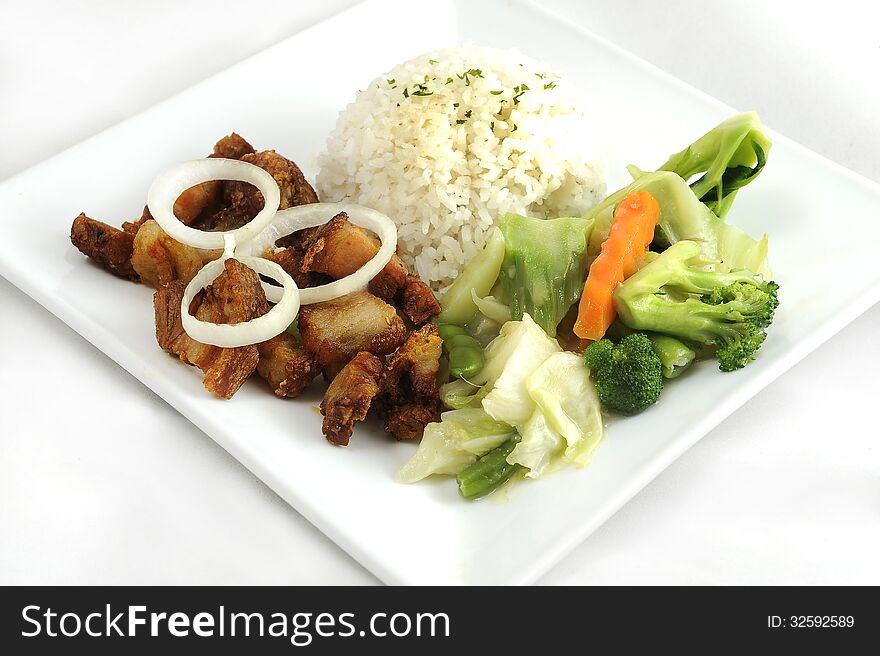 Fried pork, rice and steamed vegetables on a plate shot on white background. Fried pork, rice and steamed vegetables on a plate shot on white background