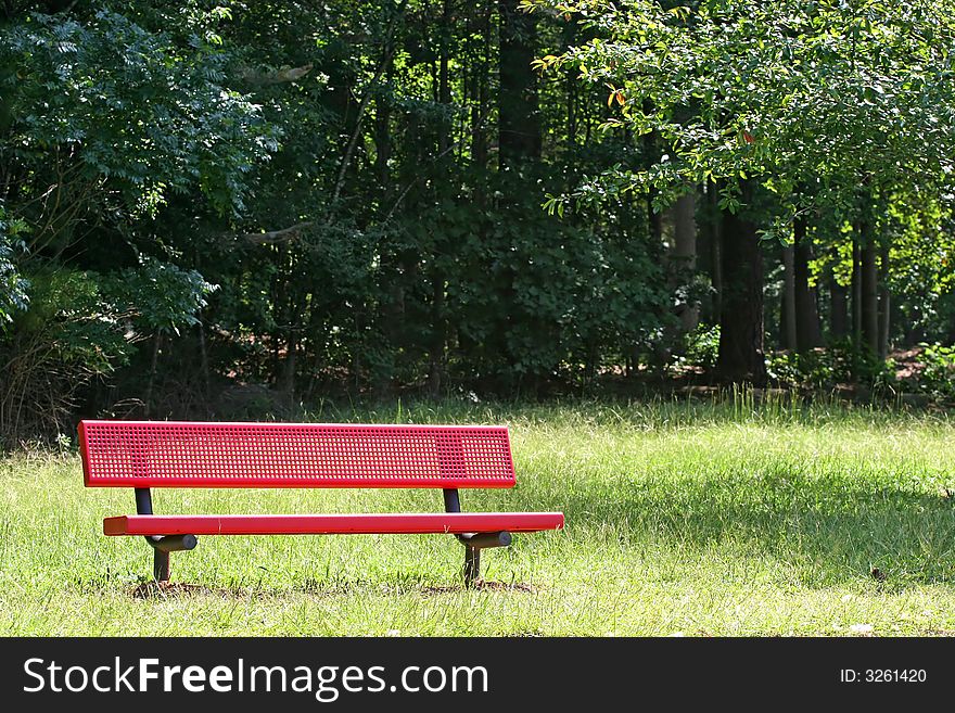 A red metal bench in  a public park. A red metal bench in  a public park