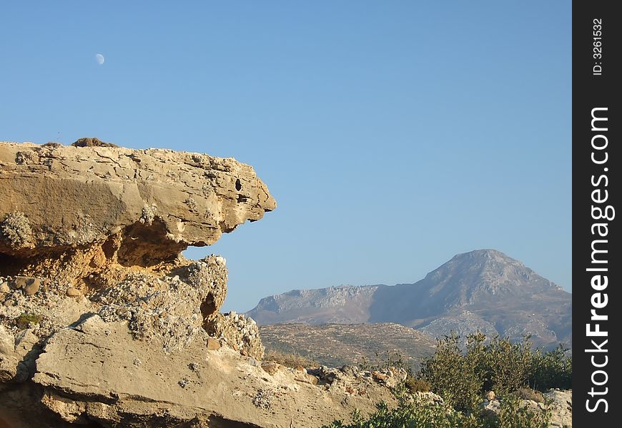 Strange shaped rock with moon above it. Strange shaped rock with moon above it