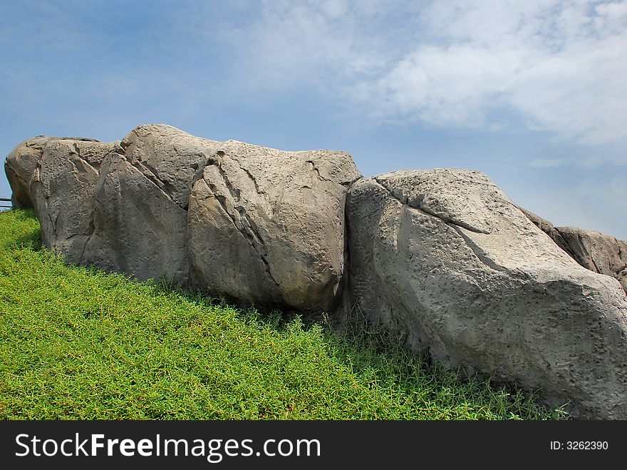 Cracked stones background with blue sky and front greegrass. Cracked stones background with blue sky and front greegrass