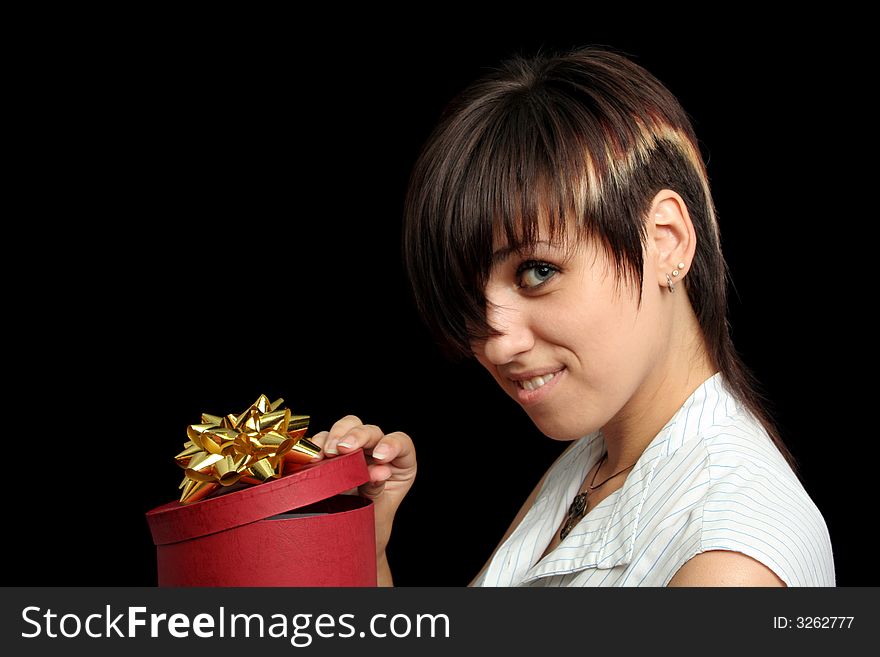 The young girl looks in a box with a gift, isolated on black background. The young girl looks in a box with a gift, isolated on black background