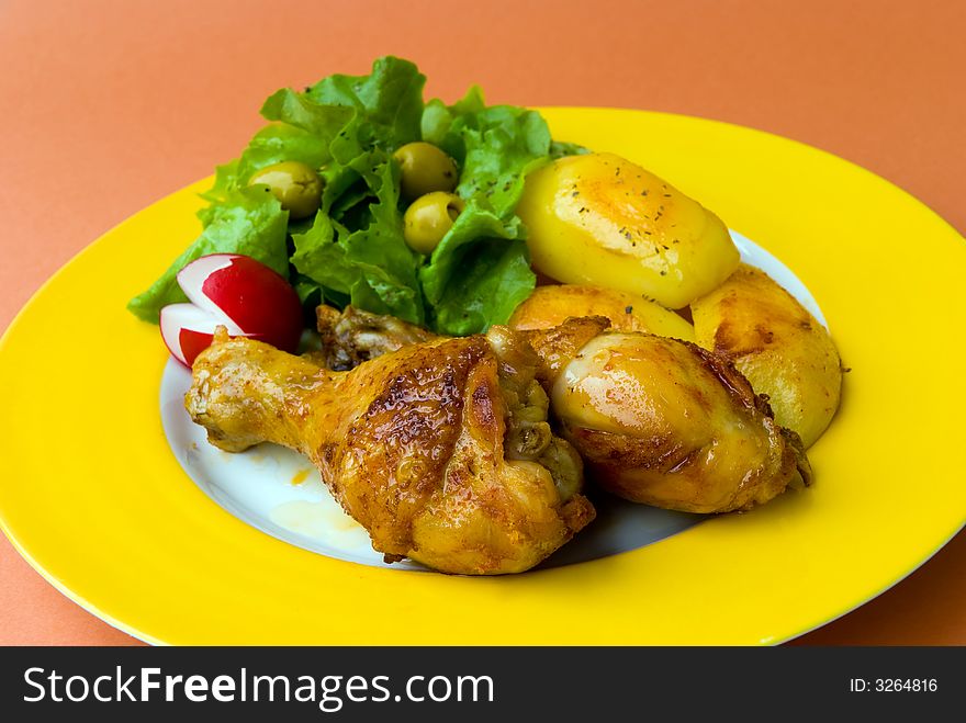 Roasted chicken legs with potatoes and salad.