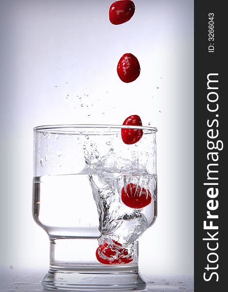 Falling red stone into glass of water. Falling red stone into glass of water