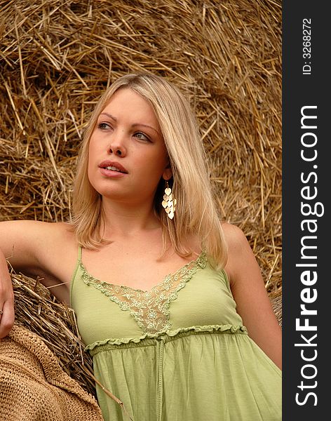 Portrait of attractive blonde leaning on hay bale. Portrait of attractive blonde leaning on hay bale.