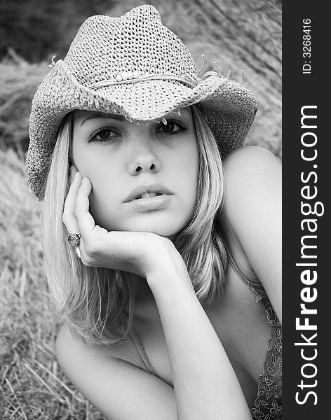 Black and white portrait of attractive blonde sitting on hay bale. Black and white portrait of attractive blonde sitting on hay bale.