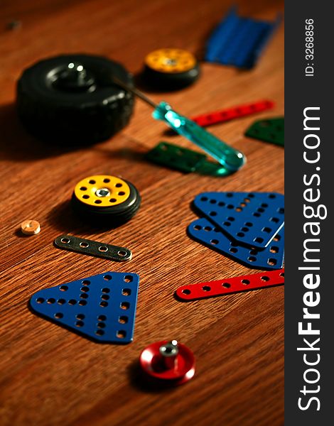 Colorful pieces of matal kit, metal sheets, wheels and a screwdriver - a toy for kids to assemble vehicles. Colorful pieces of matal kit, metal sheets, wheels and a screwdriver - a toy for kids to assemble vehicles.