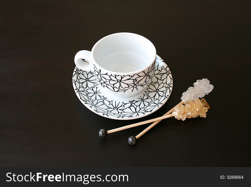 Sugar crystals and small coffee cup on a dark surface. Sugar crystals and small coffee cup on a dark surface