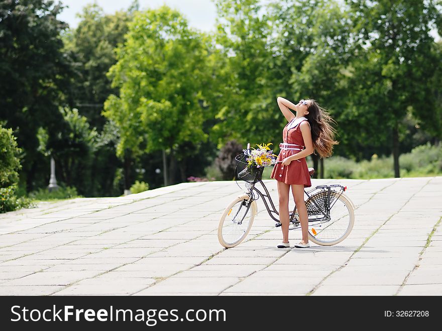 Fashion portrait of young pretty woman with bicycle and flowers