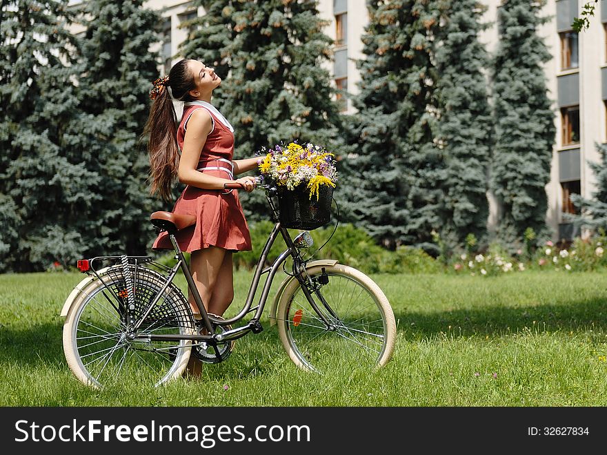 Fashion portrait of young pretty woman with bicycle and flowers