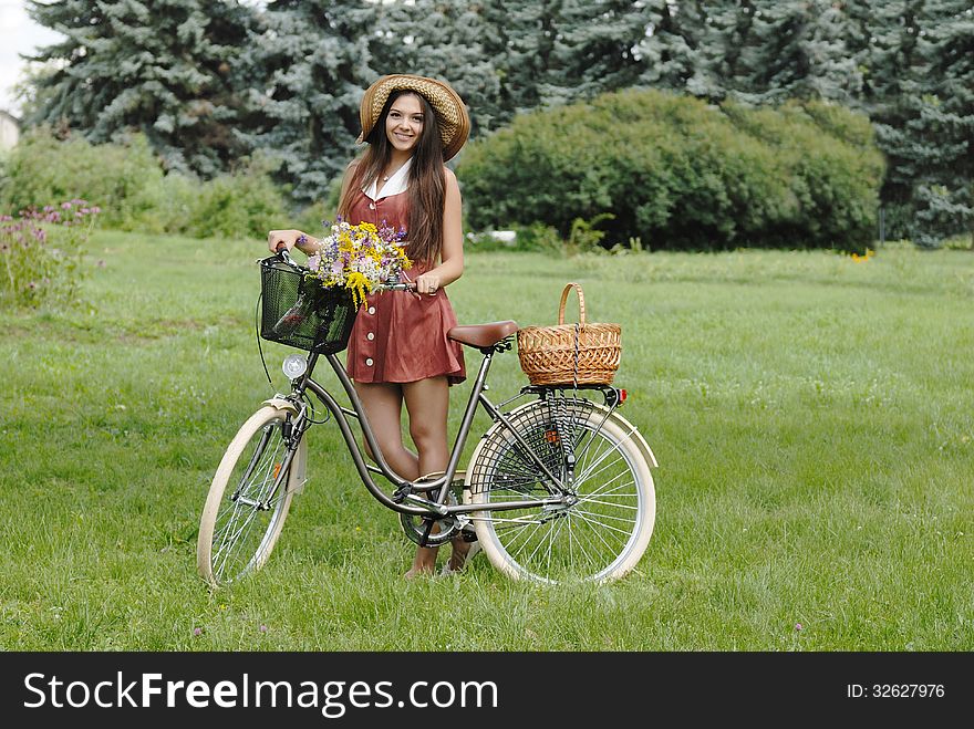 Fashion portrait of young pretty woman with bicycle and flowers